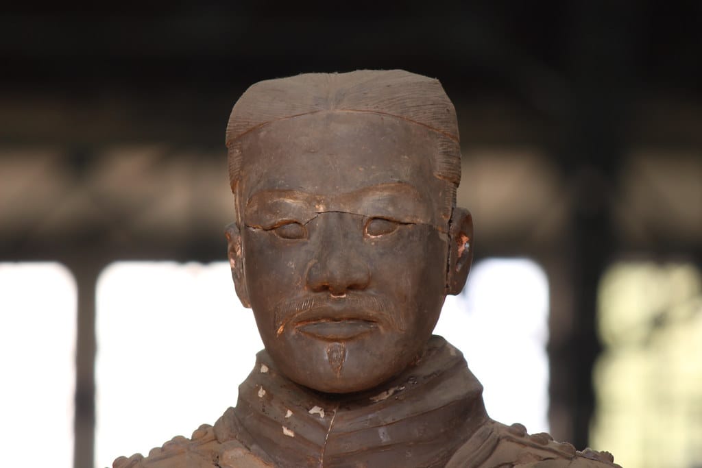 Close view of a Terracotta Army warrior's head and upper armour, showing the surface of the clay